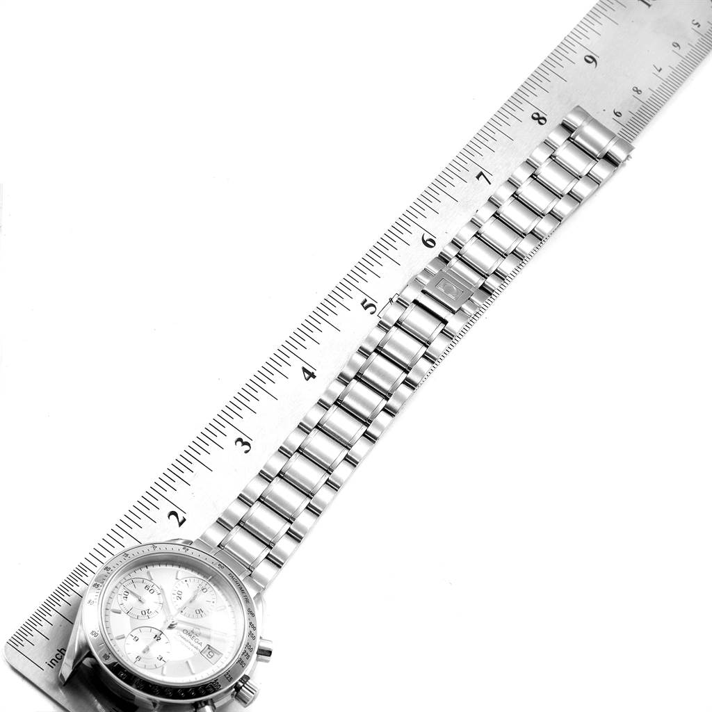 The image shows an Omega Speedmaster 3513.30.00 Men
s Stainless Steel Silver Dial 3513.30.00 Men
s Stainless Steel Silver Dial watch with a stainless steel bracelet laid next to a ruler, viewed from above.