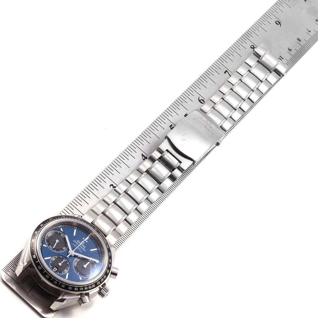 The Omega Speedmaster 326.30.40.50.03.001 Men
s Stainless Steel Blue Dial 326.30.40.50.03.001 Men
s Stainless Steel Blue Dial watch is shown from a top-down angle, displaying the face, bezel, and metal bracelet against a ruler.