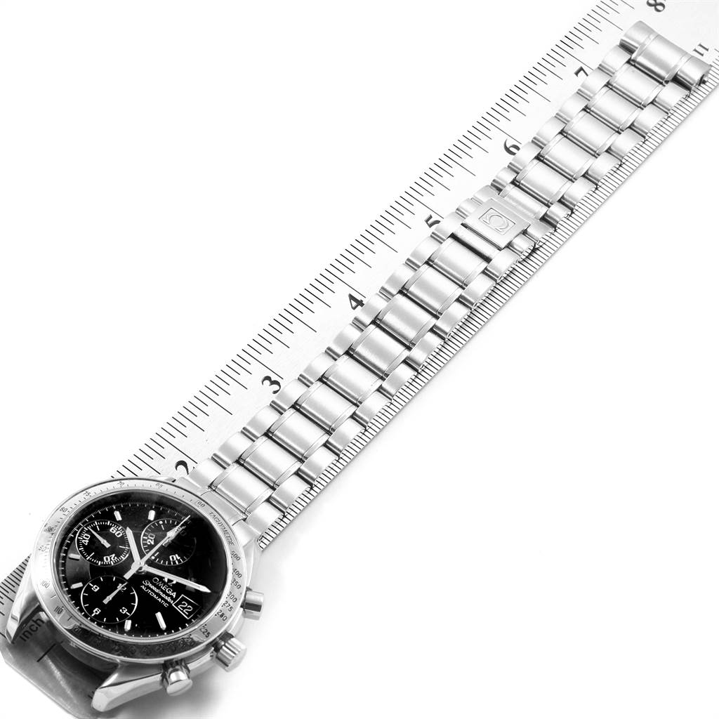 The image shows an Omega Speedmaster 3513.50.00 Men
s Stainless Steel Black Dial 3513.50.00 Men
s Stainless Steel Black Dial watch and its metal bracelet measured against a ruler from an overhead angle.