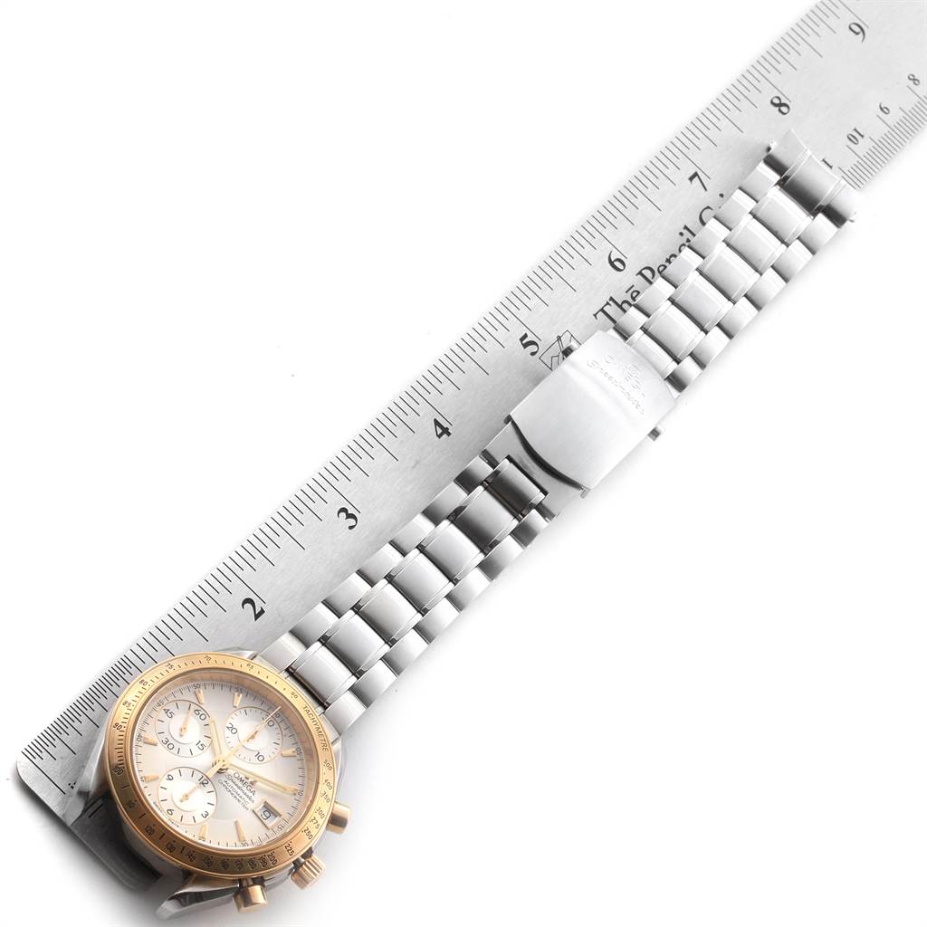 The image shows an Omega Speedmaster 323.21.40.40.02.001 Men
s Steel and Gold (two tone) Silver Dial 323.21.40.40.02.001 Men
s Steel and Gold (two tone) Silver Dial watch laid flat next to a ruler, highlighting the watch face and bracelet.
