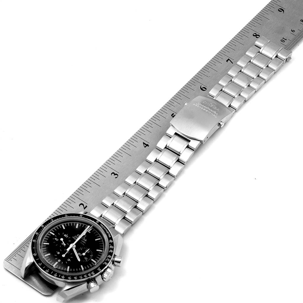 The image shows an Omega Speedmaster 3573.50.00 Men's Stainless Steel Black Dial 3573.50.00 Men's Stainless Steel Black Dial watch laid flat, with a focus on the face and metal bracelet beside a ruler.