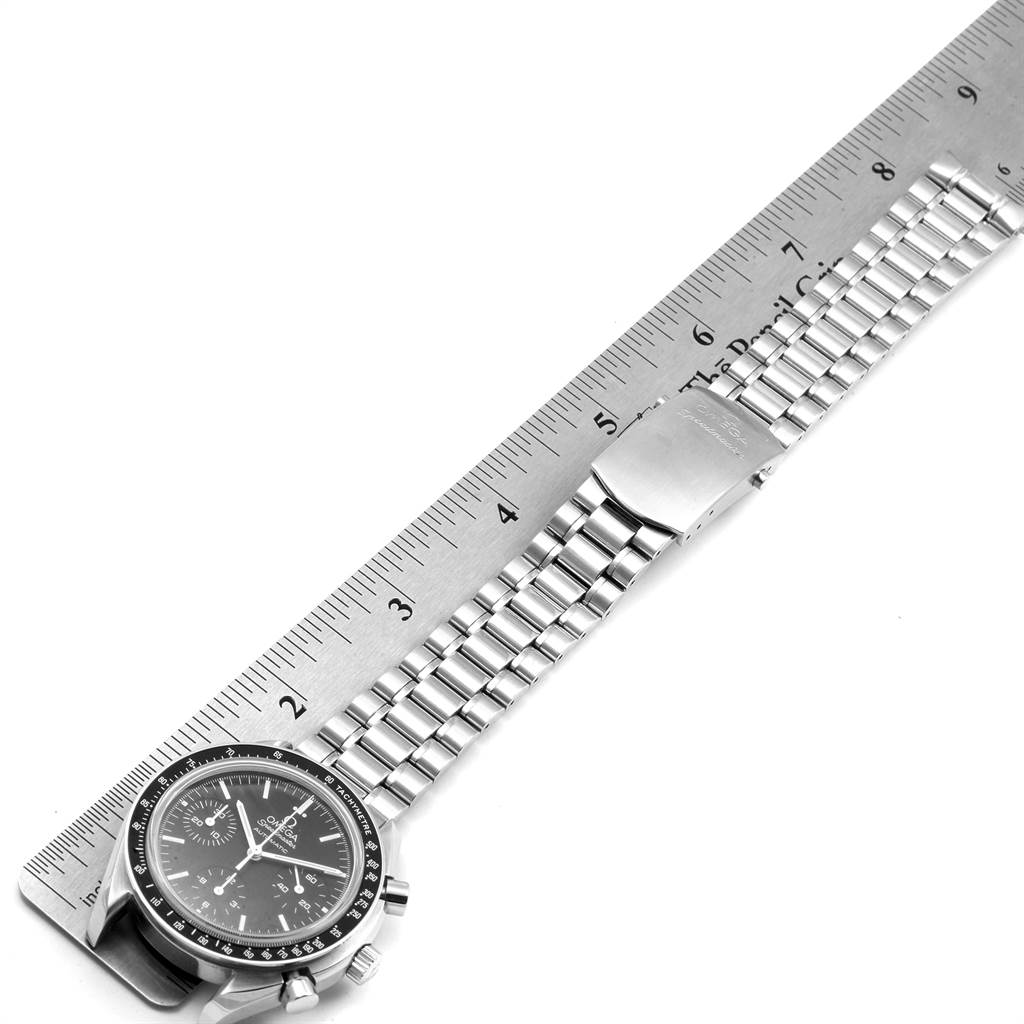 This image shows an Omega Speedmaster 3539.50.00 Men
s Stainless Steel Black Dial 3539.50.00 Men
s Stainless Steel Black Dial watch flat on a surface, measured against a metal ruler, displaying the face and band.