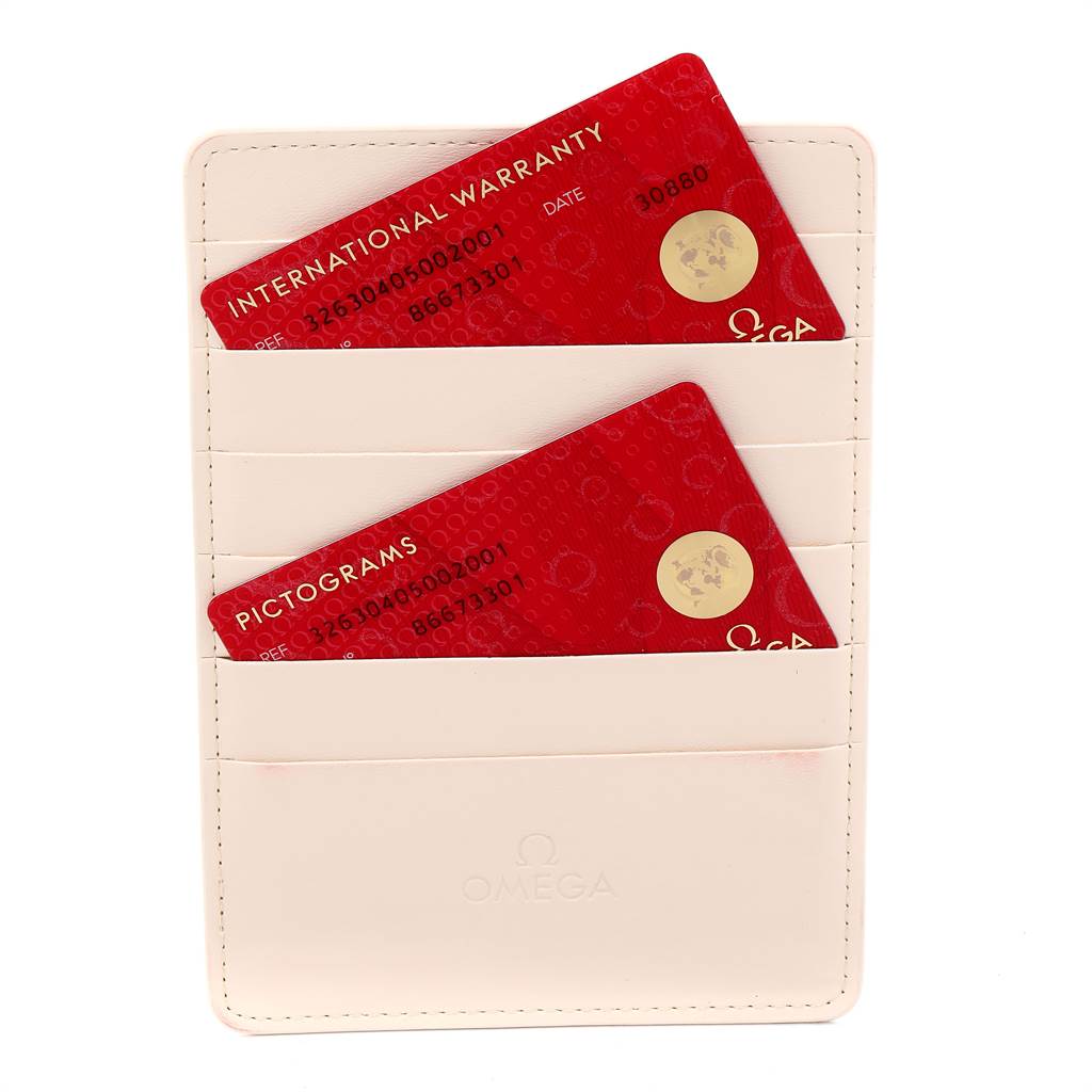 The image shows two red cards labeled "International Warranty" and "Pictograms" in a white Omega cardholder for a Speedmaster model watch.