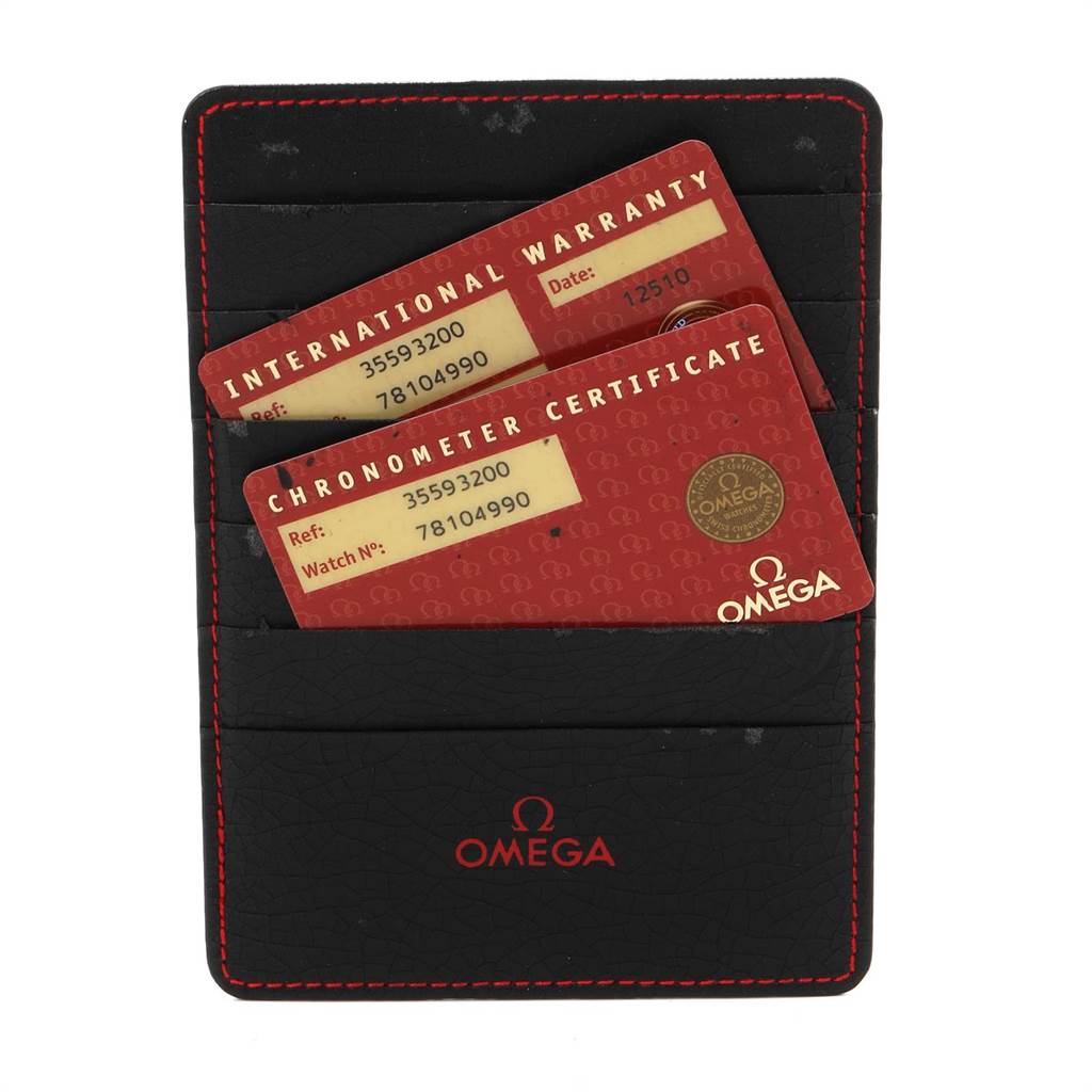 The image shows a black Omega cardholder with red stitching containing international warranty and chronometer certificate cards for a Speedmaster model.
