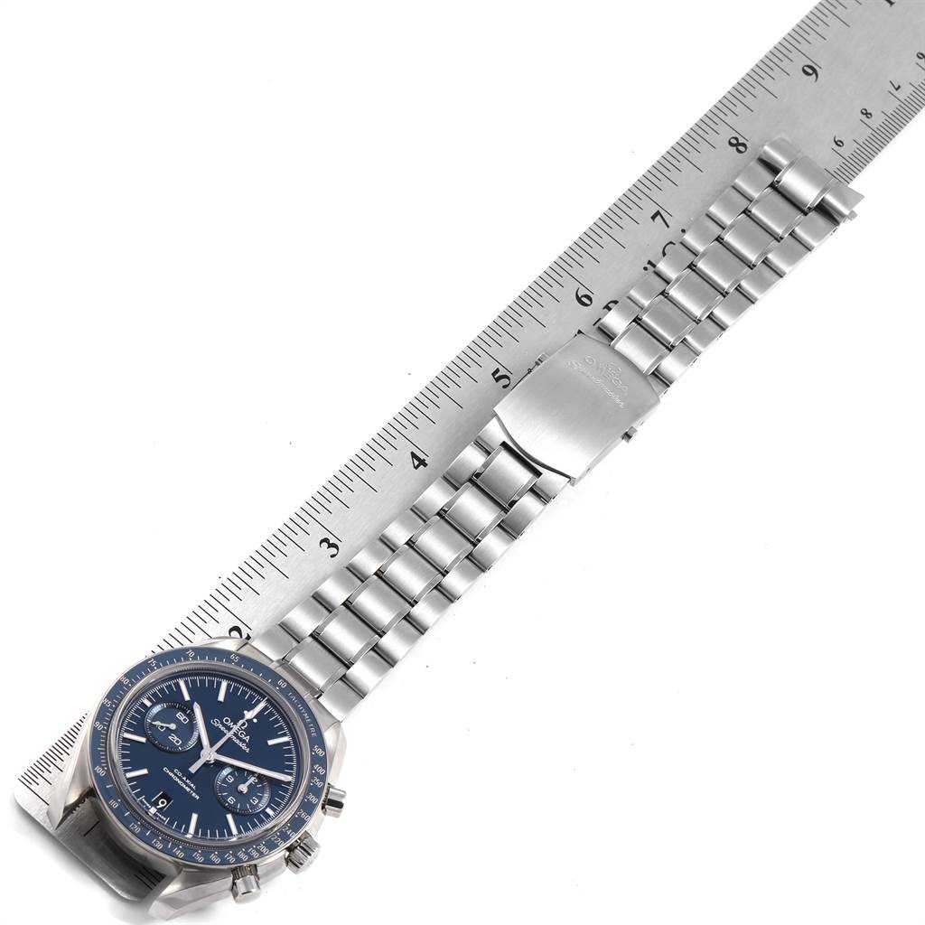 This image shows an Omega Speedmaster 311.90.44.51.03.001 Men's Titanium Blue Dial 311.90.44.51.03.001 Men's Titanium Blue Dial watch laid flat against a ruler, featuring the watch face, lugs, and metal bracelet.
