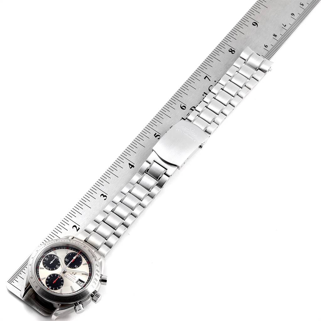 The Speedmaster by Omega is pictured from an aerial view, showing the face, bezel, full bracelet, and clasp, next to a ruler for scale.