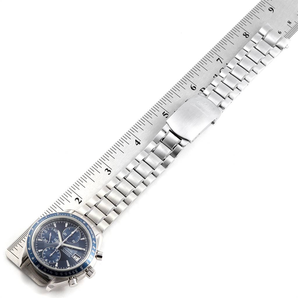 The Omega Speedmaster 3212.80.00 Men's Stainless Steel Blue Dial 3212.80.00 Men's Stainless Steel Blue Dial watch is shown laid flat next to a ruler, displaying the face and metallic bracelet.