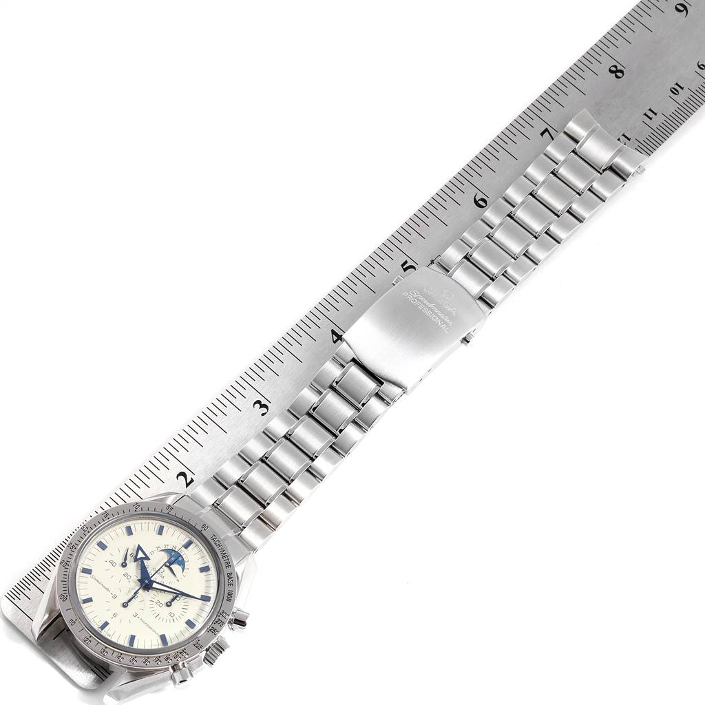 The image shows an Omega Speedmaster 3575.20.00 Men
s Stainless Steel White Dial 3575.20.00 Men
s Stainless Steel White Dial watch with a metal bracelet, clasp, and part of the face, alongside a ruler for scale.