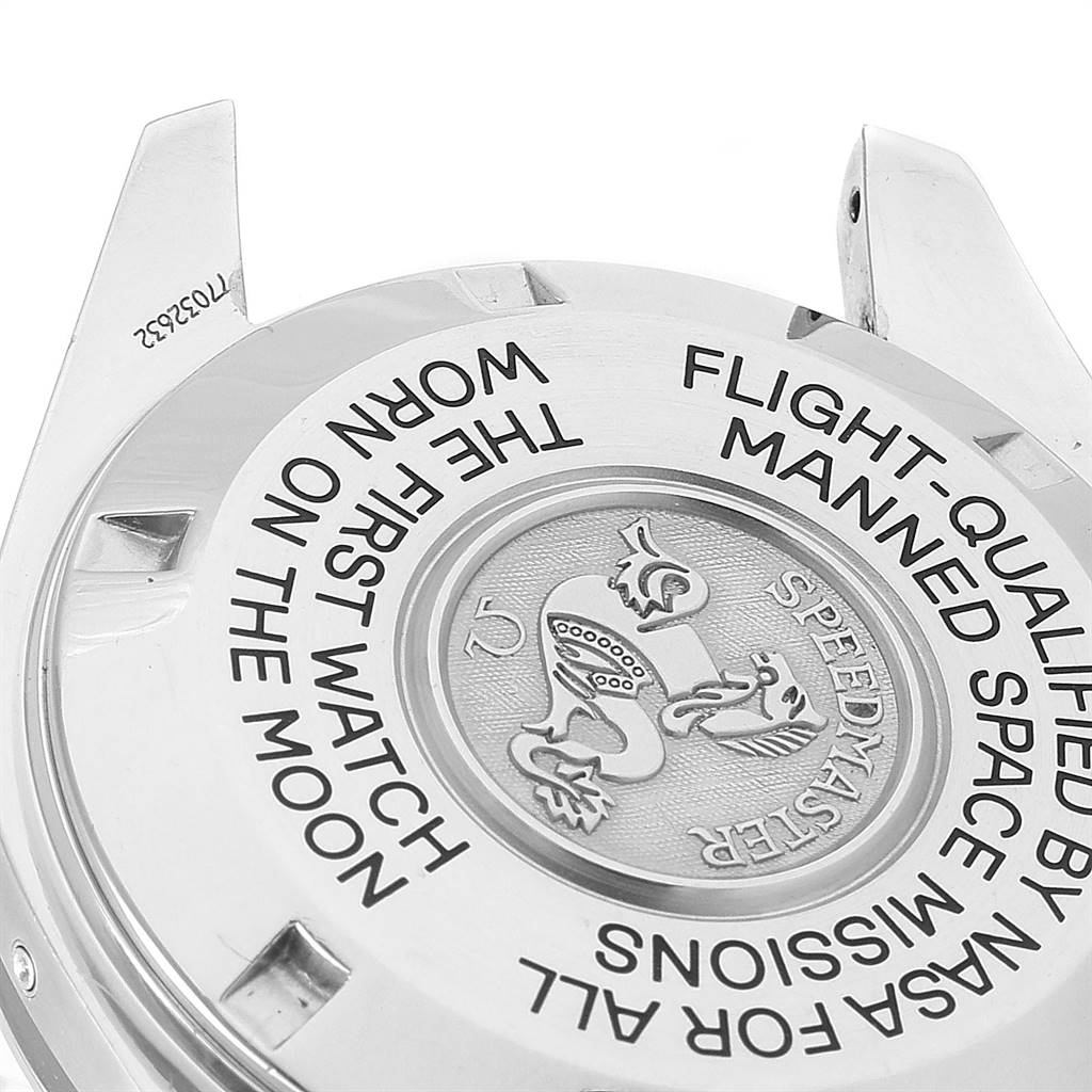 This image shows the back case of an Omega Speedmaster 3575.20.00 Men
s Stainless Steel White Dial 3575.20.00 Men
s Stainless Steel White Dial watch at an angled view, displaying engraved text and an emblem.