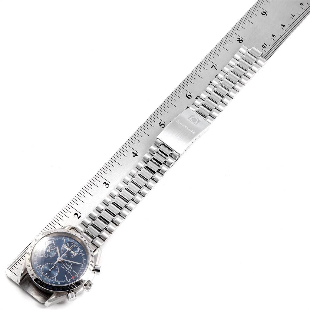 The Omega Speedmaster 3521.80.00 Men
s Stainless Steel Blue Dial 3521.80.00 Men
s Stainless Steel Blue Dial watch is displayed diagonally, showing the face and full length of the metal bracelet, measured against a ruler.