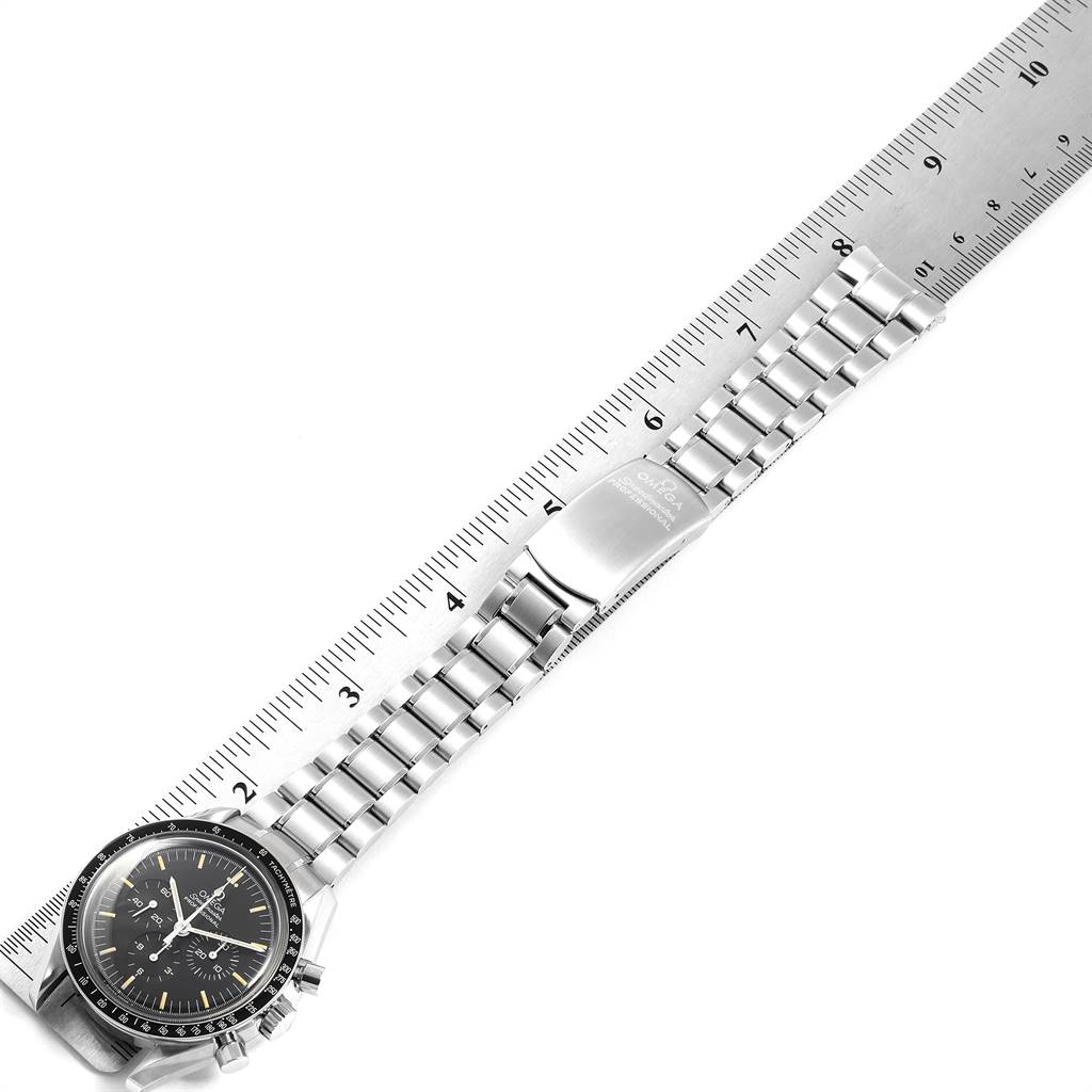 The Omega Speedmaster 3570.50.00 Men
s Stainless Steel Black Dial 3570.50.00 Men
s Stainless Steel Black Dial watch is shown fully extended with its face and metal bracelet alongside a ruler.