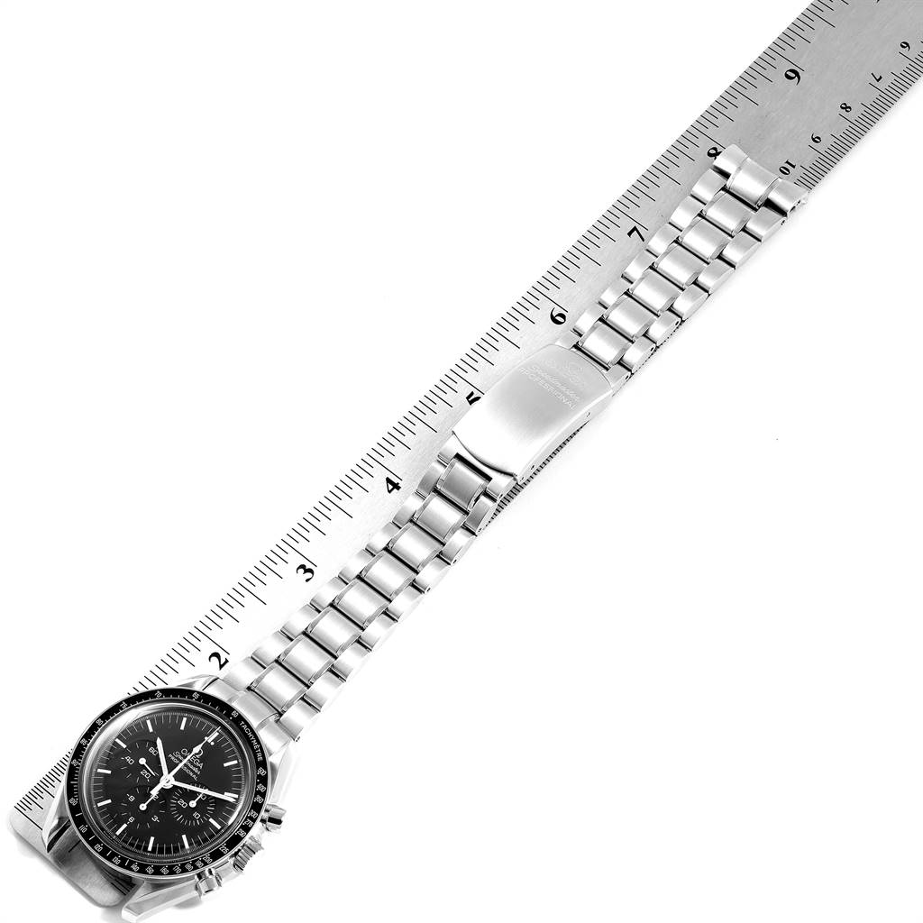 The Omega Speedmaster 3572.50.00 Men
s Stainless Steel Black Dial 3572.50.00 Men
s Stainless Steel Black Dial watch is shown from an overhead angle displaying the face, bracelet, and clasp alongside a ruler for scale.