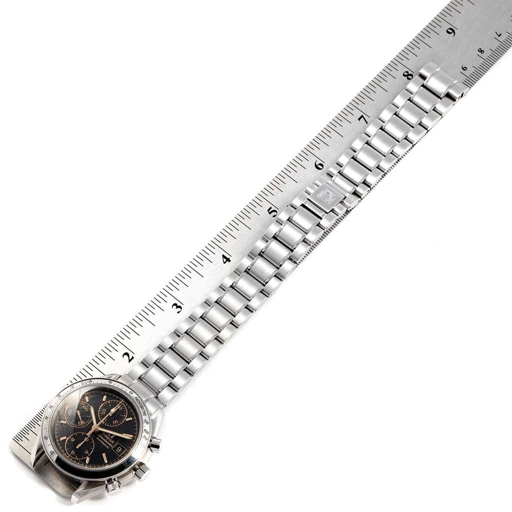 The image shows an Omega Speedmaster 3513.54.00 Men
s Stainless Steel Black Dial 3513.54.00 Men
s Stainless Steel Black Dial watch laying next to a ruler, illustrating the length of its metal bracelet.