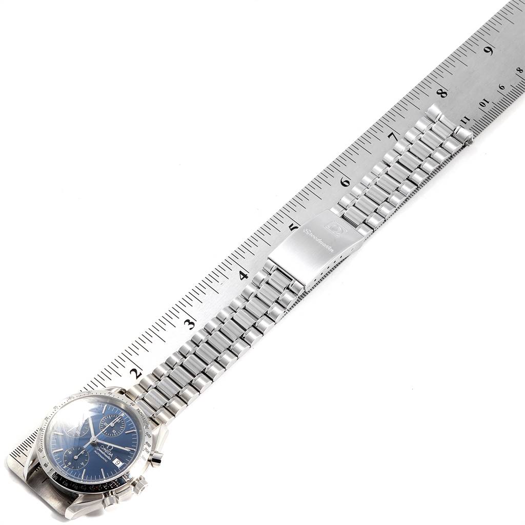 The image shows a top-down view of an Omega Speedmaster 3511.80.00 Men
s Stainless Steel Blue Dial 3511.80.00 Men
s Stainless Steel Blue Dial watch with a metal bracelet, placed next to a ruler for scale.