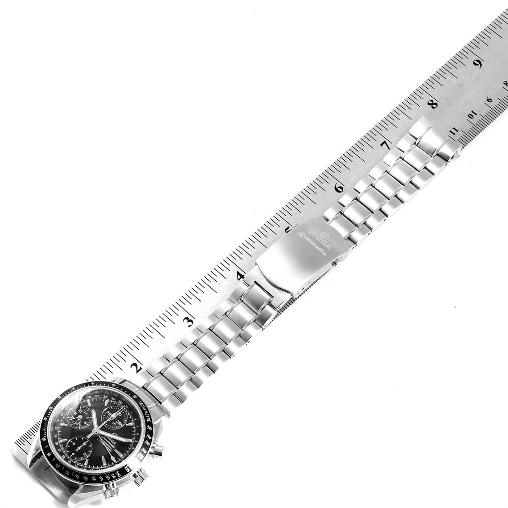 The photo shows an Omega Speedmaster 3220.50.00 Men
s Stainless Steel Black Dial 3220.50.00 Men
s Stainless Steel Black Dial watch, including its face, bezel, bracelet, and deployment clasp, positioned along a ruler.