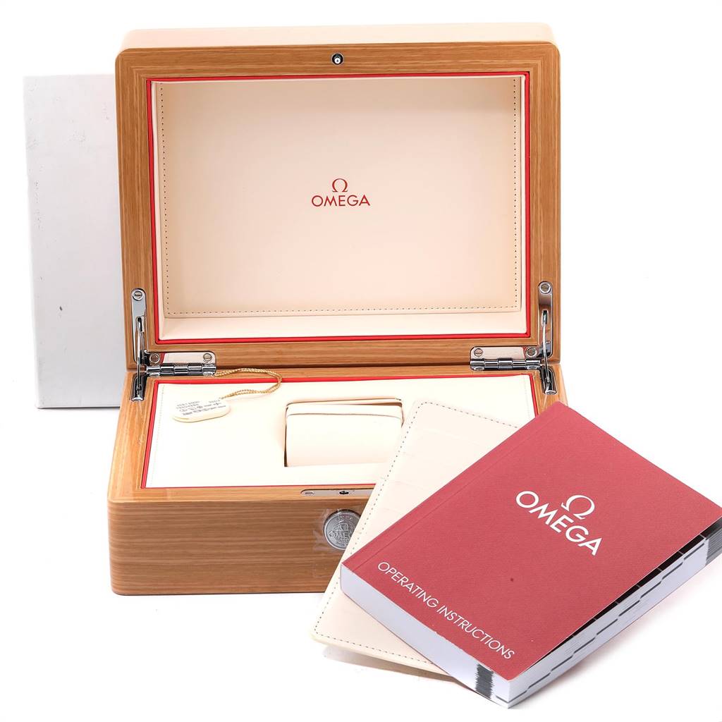 The image shows a wooden Omega Speedmaster 3581.30.00 Men's Stainless Steel White Dial 3581.30.00 Men's Stainless Steel White Dial watch box, a tag, an empty cushion, and an operating instructions manual.