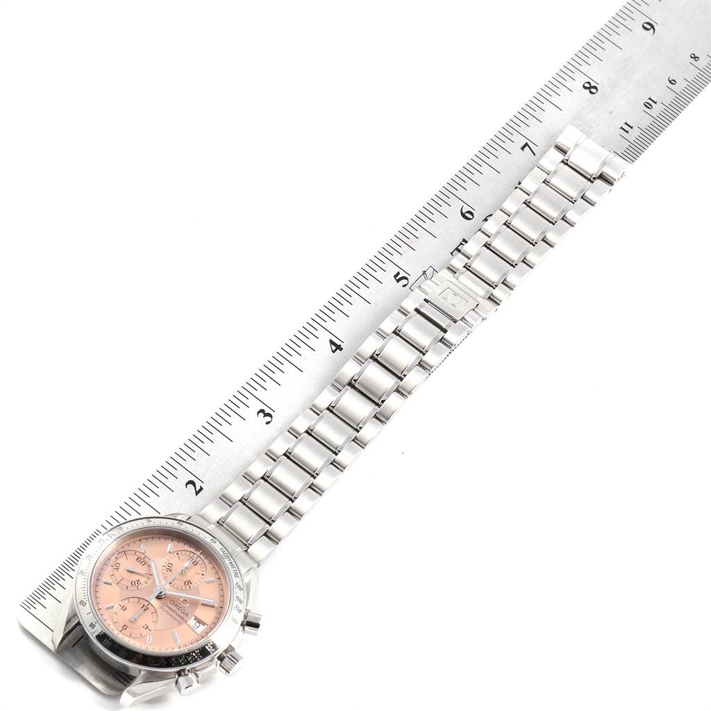 The image shows an overhead view of an Omega Speedmaster 3513.60.00 Men's Stainless Steel Pink Dial 3513.60.00 Men's Stainless Steel Pink Dial watch, focusing on its bracelet and pink dial, along with a ruler.