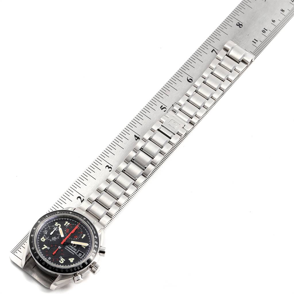 The image shows an Omega Speedmaster 3513.53.00 Men
s Stainless Steel Black Dial 3513.53.00 Men
s Stainless Steel Black Dial watch placed on a ruler, highlighting the watch face, bezel, and metal bracelet.