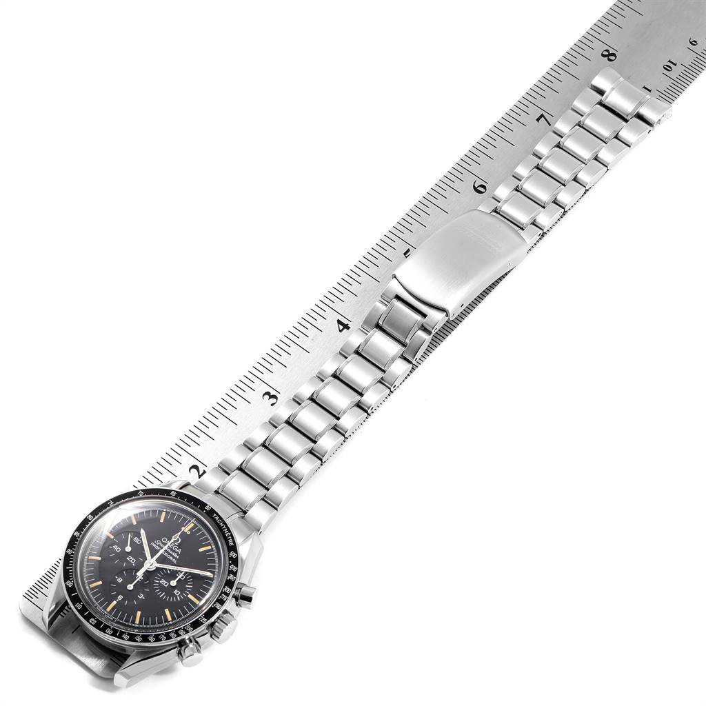 This image shows the Omega Speedmaster 145.022 Men's Stainless Steel Black Dial 145.022 Men's Stainless Steel Black Dial watch lying flat with its metal bracelet extended against a ruler.