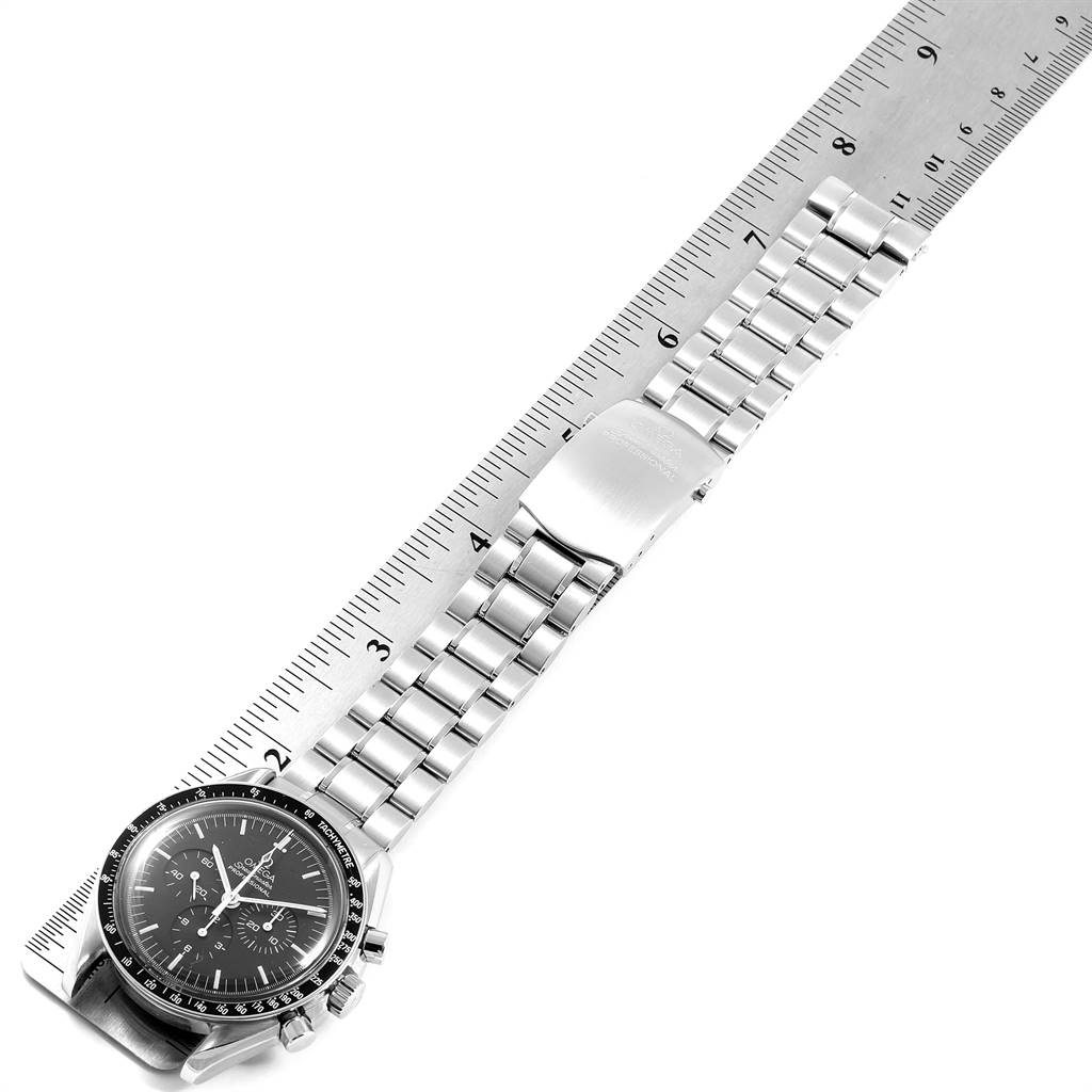 The image shows a top view of the Omega Speedmaster 3590.50.00 Men's Stainless Steel Black Dial 3590.50.00 Men's Stainless Steel Black Dial with its dial and metal bracelet alongside a measuring ruler.