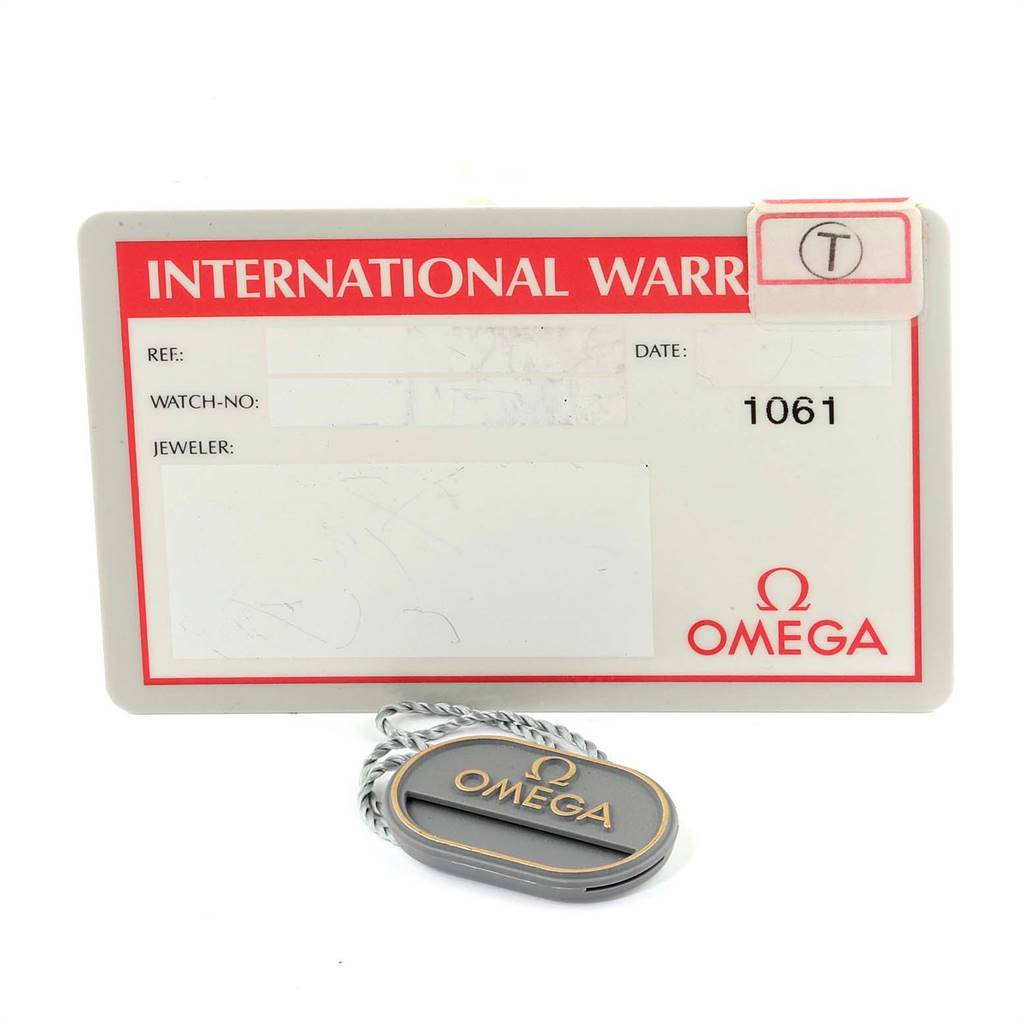 The image shows an Omega Speedmaster 3511.80.00 Men
s Stainless Steel Blue Dial 3511.80.00 Men
s Stainless Steel Blue Dial International Warranty card and an Omega tag, viewed from the front.