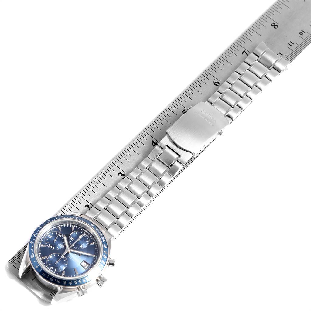 The image shows the Omega Speedmaster 3212.80.00 Men
s Stainless Steel Blue Dial 3212.80.00 Men
s Stainless Steel Blue Dial watch at an angle displaying its face, stainless steel bracelet, and clasp aligned along a ruler.