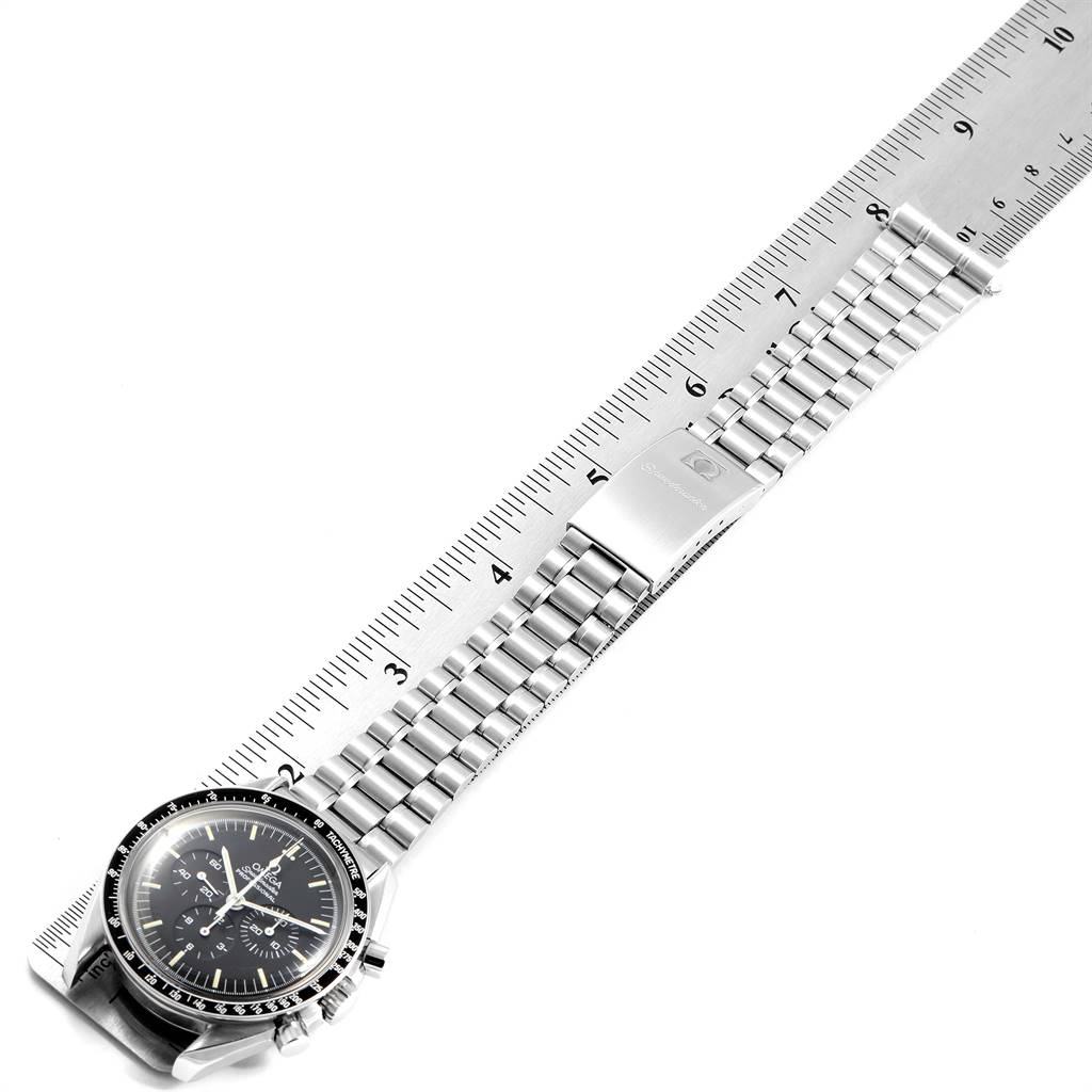 The Omega Speedmaster 3570.50.00 Men
s Stainless Steel Black Dial 3570.50.00 Men
s Stainless Steel Black Dial watch is shown from a top-down angle, highlighting the entire bracelet, clasp, and face next to a ruler.