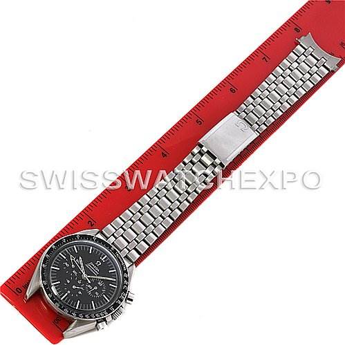 The image shows an Omega Speedmaster Men's Stainless Steel Black Dial Men's Stainless Steel Black Dial watch from a top-down angle, with the stainless steel bracelet fully extended alongside a red ruler.