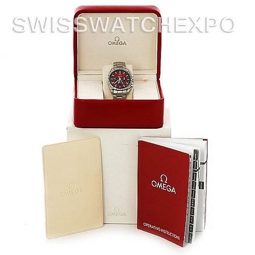 The image shows an Omega Speedmaster 3506.61 Stainless Steel Red Dial 3506.61 Stainless Steel Red Dial watch in an open box with manuals and a cardholder placed beside it.
