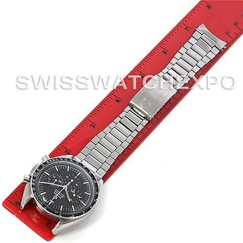 The Omega Speedmaster Men
s Stainless Steel Black Dial Men
s Stainless Steel Black Dial watch is displayed from an overhead angle, showing its face, bezel, bracelet, and clasp, laid on a red ruler.