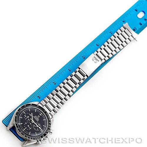 The image shows an Omega Speedmaster Men
s Stainless Steel Black Dial Men
s Stainless Steel Black Dial watch laid flat alongside a blue ruler, displaying its face, bracelet, and clasp.