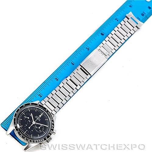 The image shows an Omega Speedmaster 105.003-65 Men
s Stainless Steel Black Dial 105.003-65 Men
s Stainless Steel Black Dial watch laid flat on a surface next to a ruler, displaying its face and metal bracelet fully.