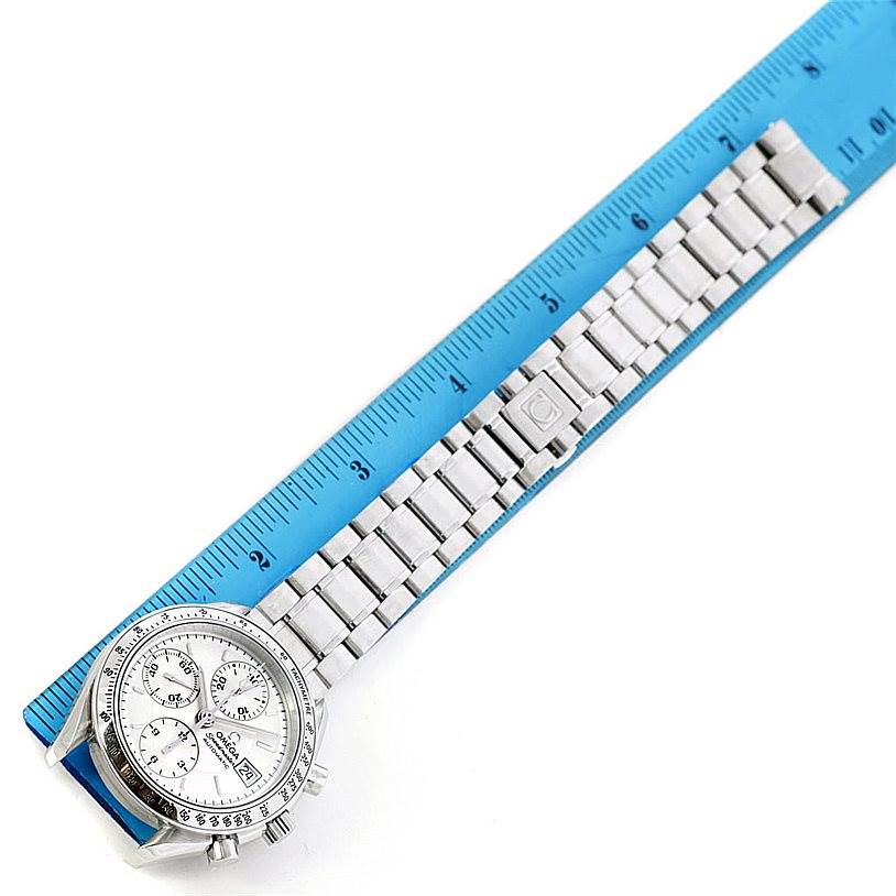 The image shows an Omega Speedmaster 3513.30.00 Men
s Stainless Steel Silver Dial 3513.30.00 Men
s Stainless Steel Silver Dial watch at an angle, displaying the face and metal band laid along a ruler.