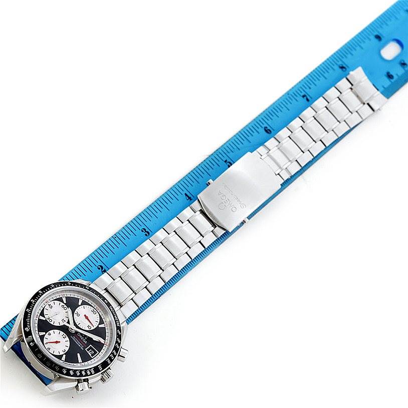 The image shows an Omega Speedmaster 3210.51.00 Men's Stainless Steel Black Dial 3210.51.00 Men's Stainless Steel Black Dial watch from a top view, laying beside a blue ruler, highlighting its full metal bracelet and clasp.