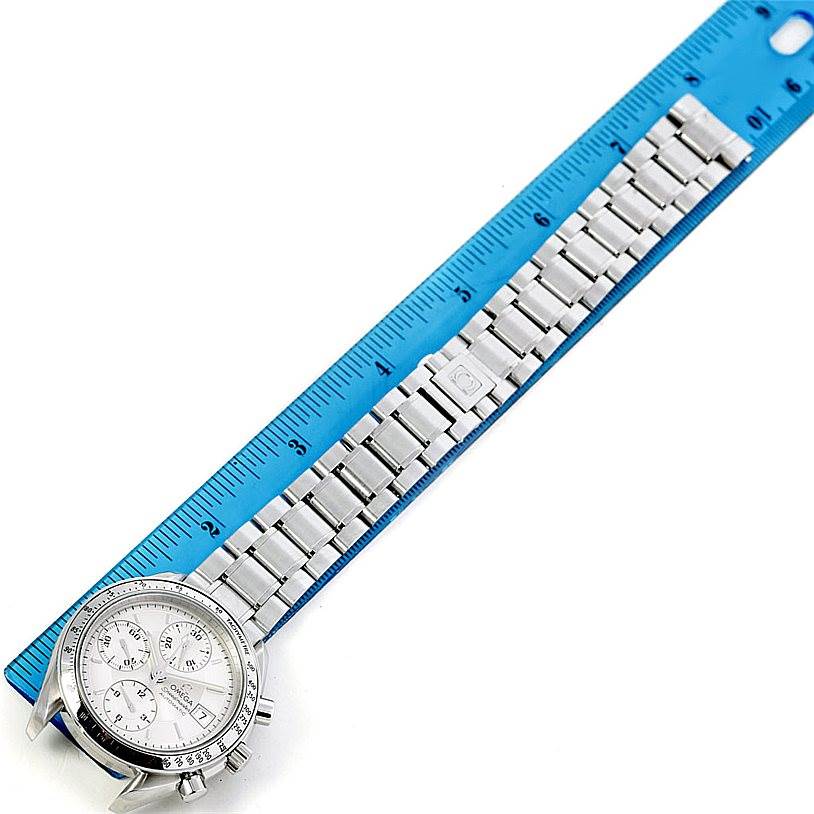 The image shows an Omega Speedmaster 3513.30.00 Men
s Stainless Steel Silver Dial 3513.30.00 Men
s Stainless Steel Silver Dial watch and its band alongside a blue ruler, viewed from a top-down angle.