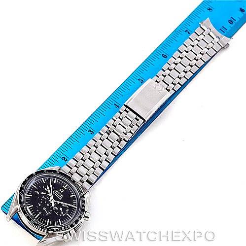 The image shows an Omega Speedmaster Men
s Stainless Steel Black Dial Men
s Stainless Steel Black Dial watch laid flat on a blue ruler, displaying the face, stainless steel bracelet, and clasp.
