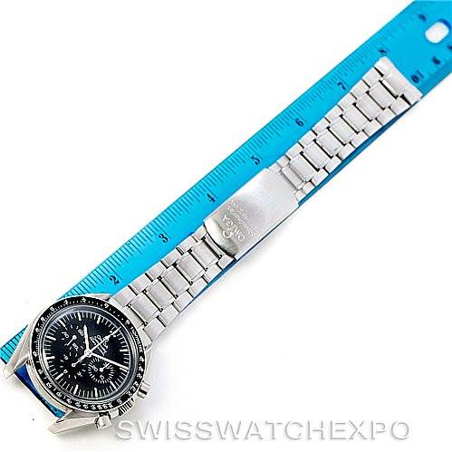 The Omega Speedmaster Men
s Stainless Steel Black Dial Men
s Stainless Steel Black Dial watch is shown from an overhead angle, displaying its face and stainless steel bracelet resting alongside a blue ruler.