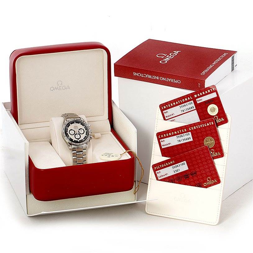 The image shows an Omega Speedmaster 3506.31.00 Men
s Stainless Steel Silver Dial 3506.31.00 Men
s Stainless Steel Silver Dial watch in its open box, with warranty and certification cards, and an instruction book nearby.