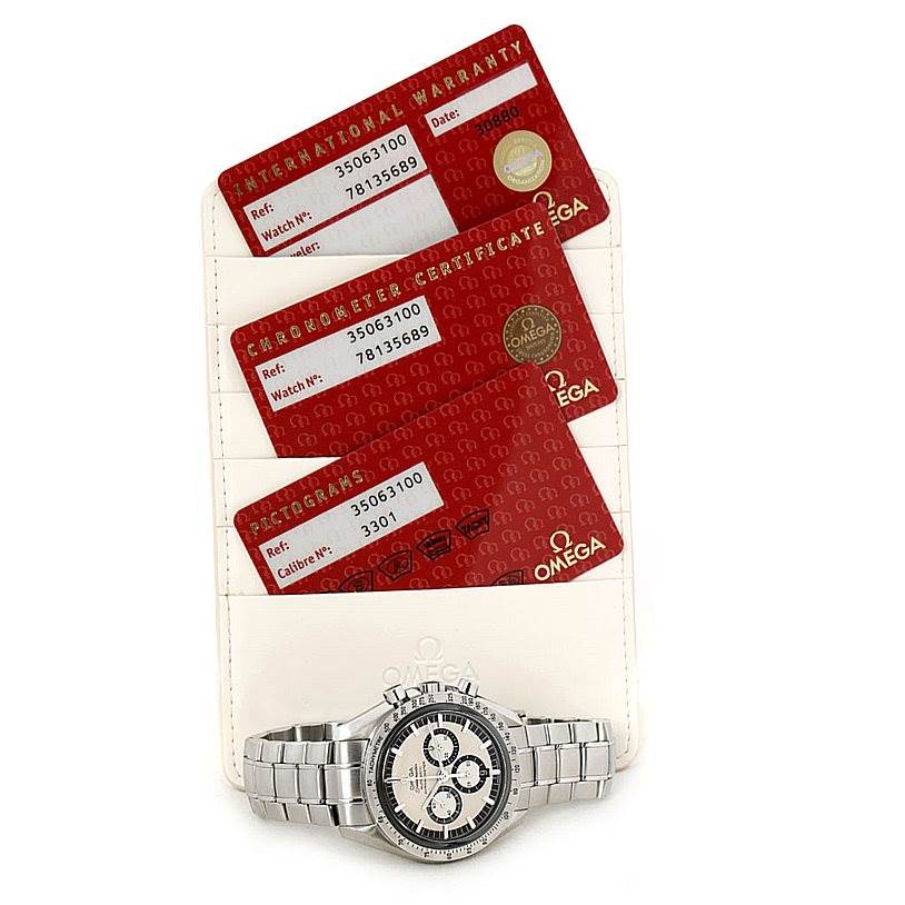 The image shows an Omega Speedmaster 3506.31.00 Men
s Stainless Steel Silver Dial 3506.31.00 Men
s Stainless Steel Silver Dial watch laid flat, accompanied by international warranty, chronometer certificate, and pictogram cards.