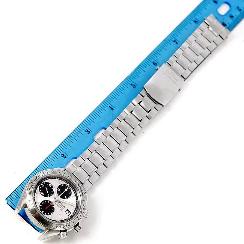 The image shows an Omega Speedmaster 3211.31.00 Men
s Stainless Steel Silver Dial 3211.31.00 Men
s Stainless Steel Silver Dial watch laid flat with its metal bracelet next to a blue ruler for measurement.