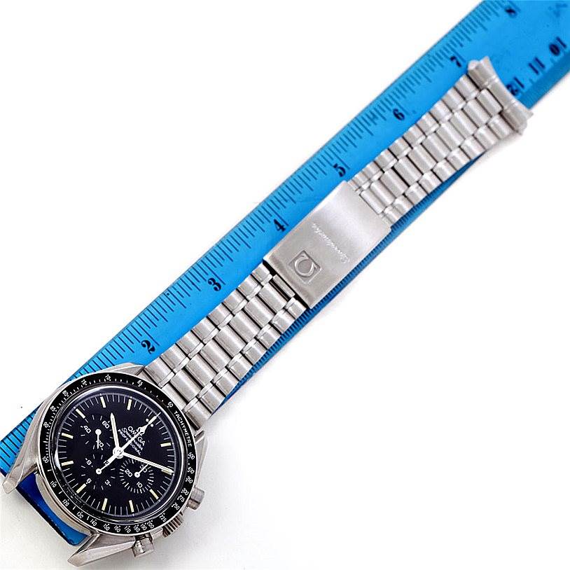 The Omega Speedmaster Men
s Stainless Steel Black Dial Men
s Stainless Steel Black Dial watch is shown front-facing with its bracelet partially extended alongside a ruler for scale.