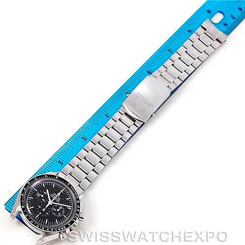 The image shows an Omega Speedmaster 3570.50.00 Men
s Stainless Steel Black Dial 3570.50.00 Men
s Stainless Steel Black Dial watch laying flat, with its face, bracelet, and clasp visible, next to a blue ruler.