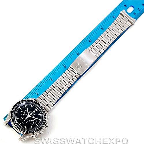 The image shows an Omega Speedmaster Men
s Stainless Steel Black Dial Men
s Stainless Steel Black Dial watch laid flat with its metal bracelet next to a blue ruler for scale.