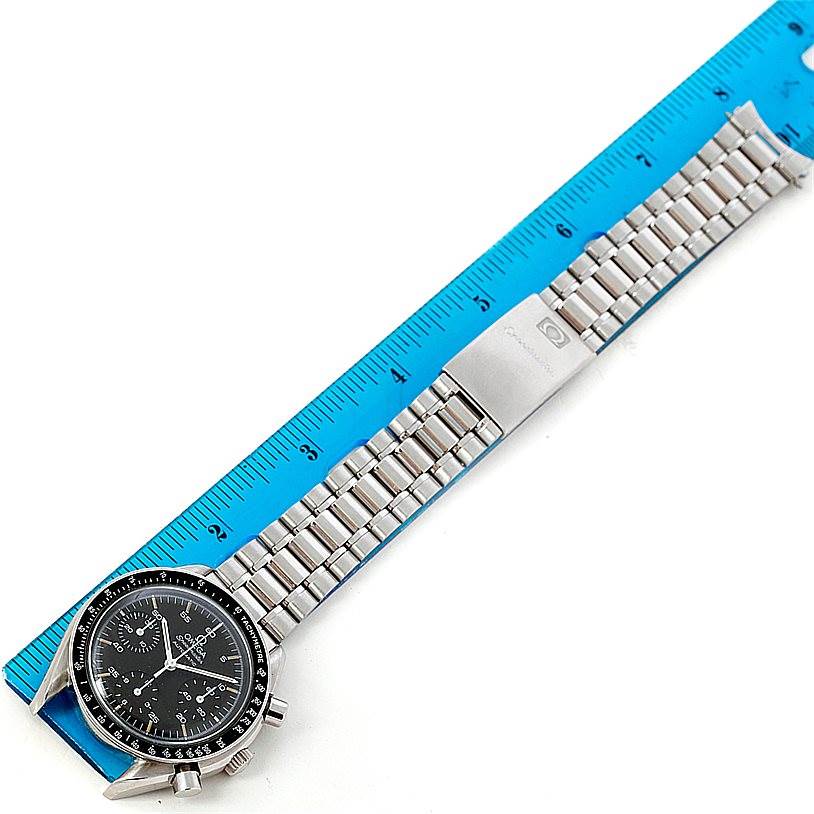 The image shows an Omega Speedmaster 3510.50.00 Men
s Stainless Steel Black Dial 3510.50.00 Men
s Stainless Steel Black Dial watch laid flat with its metal bracelet extended next to a blue ruler for scale.