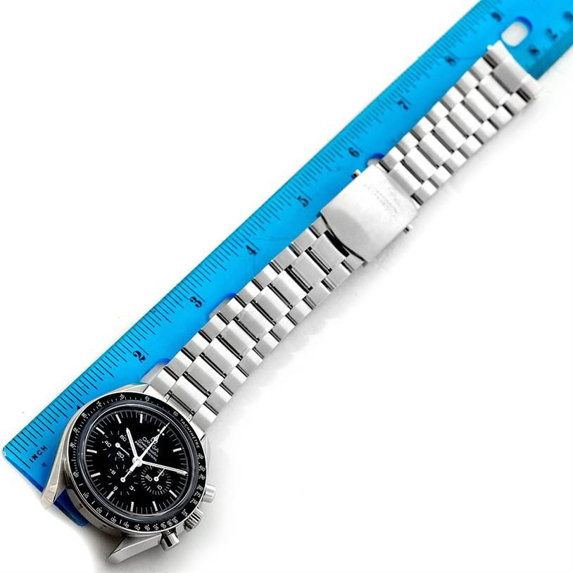 The image shows an Omega Speedmaster 3573.50.00 Men
s Stainless Steel Black Dial 3573.50.00 Men
s Stainless Steel Black Dial watch focused on its face and stainless steel bracelet, measured against a blue ruler.