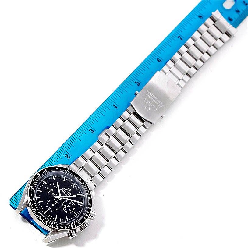The image shows an Omega Speedmaster 3570.50.00 Men
s Stainless Steel Black Dial 3570.50.00 Men
s Stainless Steel Black Dial watch laid flat with a blue ruler for scale.