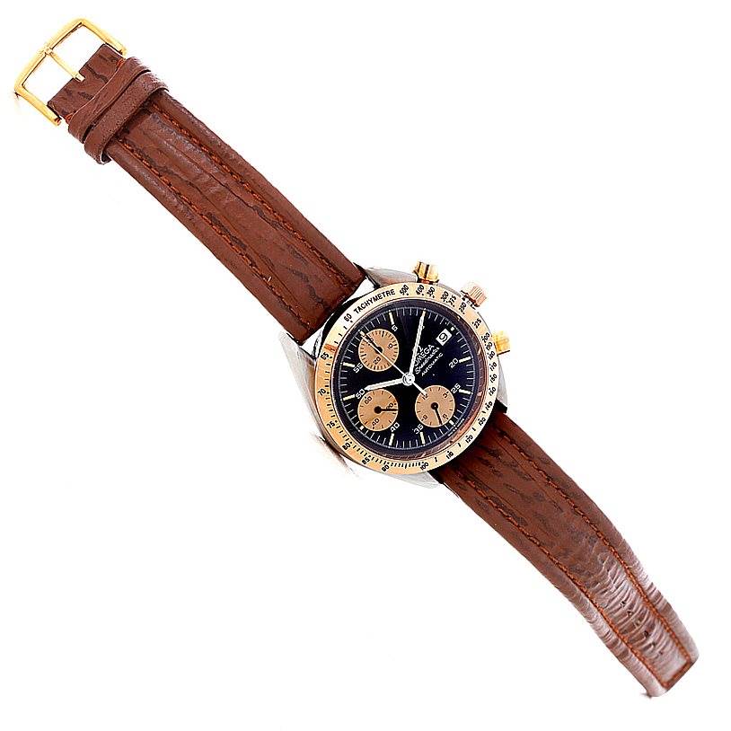 The Omega Speedmaster 3716.50.00 Men
s Stainless Steel Black Dial 3716.50.00 Men
s Stainless Steel Black Dial watch is shown from a top-down angle, highlighting its brown leather strap, black dial, and gold-tone bezel.