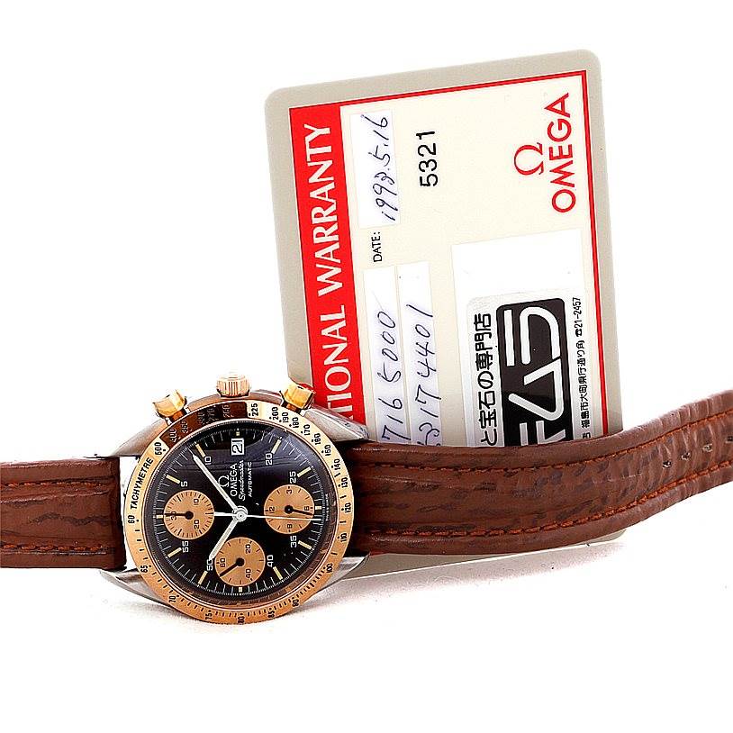 The image shows an Omega Speedmaster 3716.50.00 Men
s Stainless Steel Black Dial 3716.50.00 Men
s Stainless Steel Black Dial watch face and strap, along with its international warranty card placed behind it.