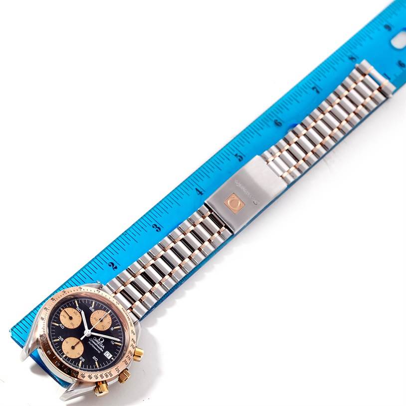 This image shows an Omega Speedmaster 3716.50.00 Men
s Stainless Steel Black Dial 3716.50.00 Men
s Stainless Steel Black Dial watch laid flat next to a ruler, displaying its face and metal bracelet.