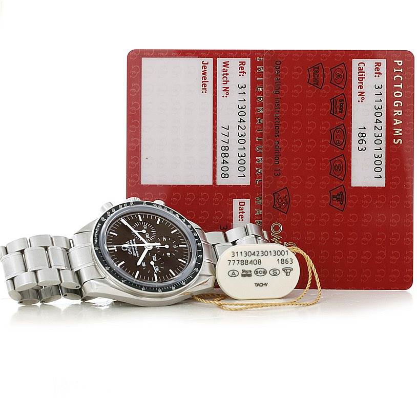 The image shows an Omega Speedmaster 311.30.42.30.13.001 Men's Stainless Steel Brown Dial 311.30.42.30.13.001 Men's Stainless Steel Brown Dial watch lying flat with cards and a tag in the background.